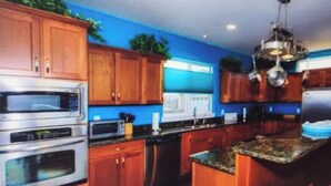 Una cocina con armarios de madera, electrodomésticos de acero inoxidable y encimera de granito.