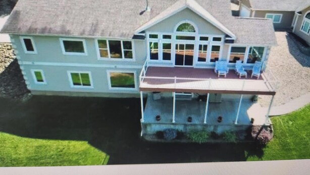 Una casa de dos pisos con balcón, ventanas amplias y un patio cubierto.