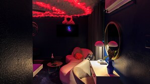 Une pièce moderne avec un plafond éclairé de lumière rouge, un canapé, une petite table avec une lampe et un miroir.