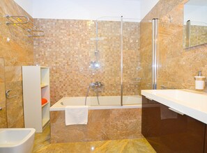 A modern bathroom with a glass-enclosed shower, a freestanding bathtub, and a vanity with a mirror.