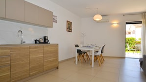 A modern kitchen with a dining area, featuring a white table, black and white chairs, and a coffee machine. - Family Friendly Spacious Apartment With Garden and Terrace (Rovinj)