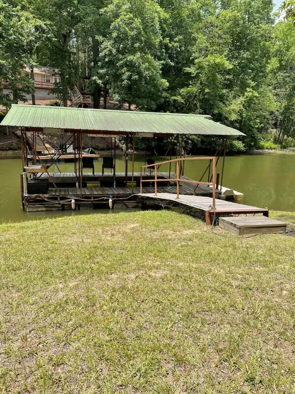 A wooden dock with a covered seating area and a small building in the background.
