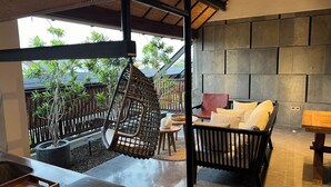A modern outdoor seating area with a hanging chair, cushioned seating, and a stone wall backdrop.