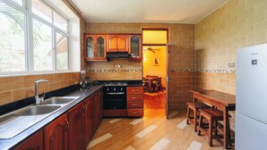 A kitchen with wooden cabinets, a stove, and a refrigerator. - Amariah Apartments TPDC Mikocheni (Dar es Salaam)