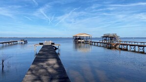 Eine Anlegestelle, die in ruhiges Wasser führt, mit einer überdachten Sitzgelegenheit und einem kleinen Bauwerk am Ende.