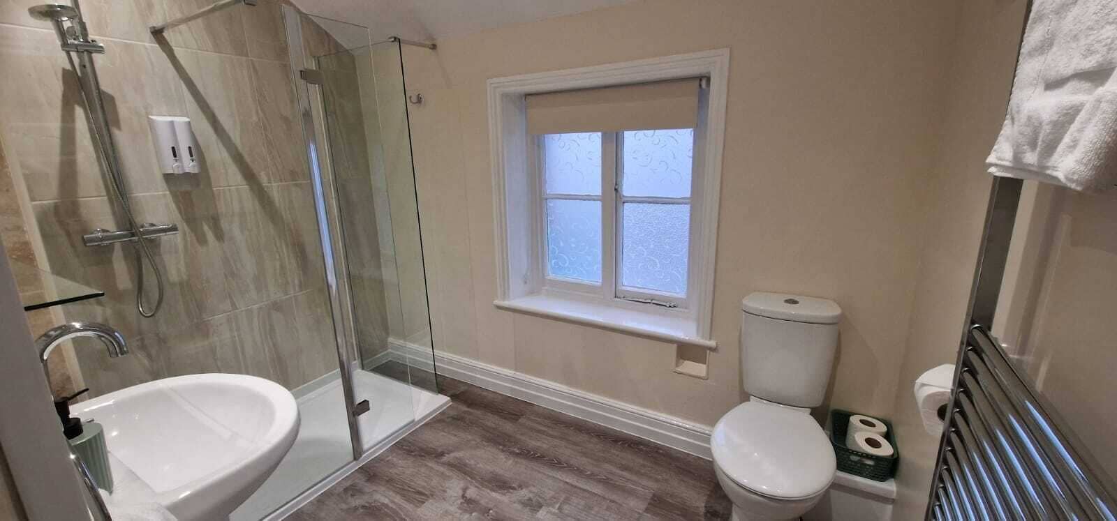 Une salle de bain avec une douche à parois de verre, des toilettes et un lavabo.