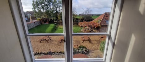 Une fenêtre donnant sur un jardin, une terrasse en bois et un bâtiment en briques.
