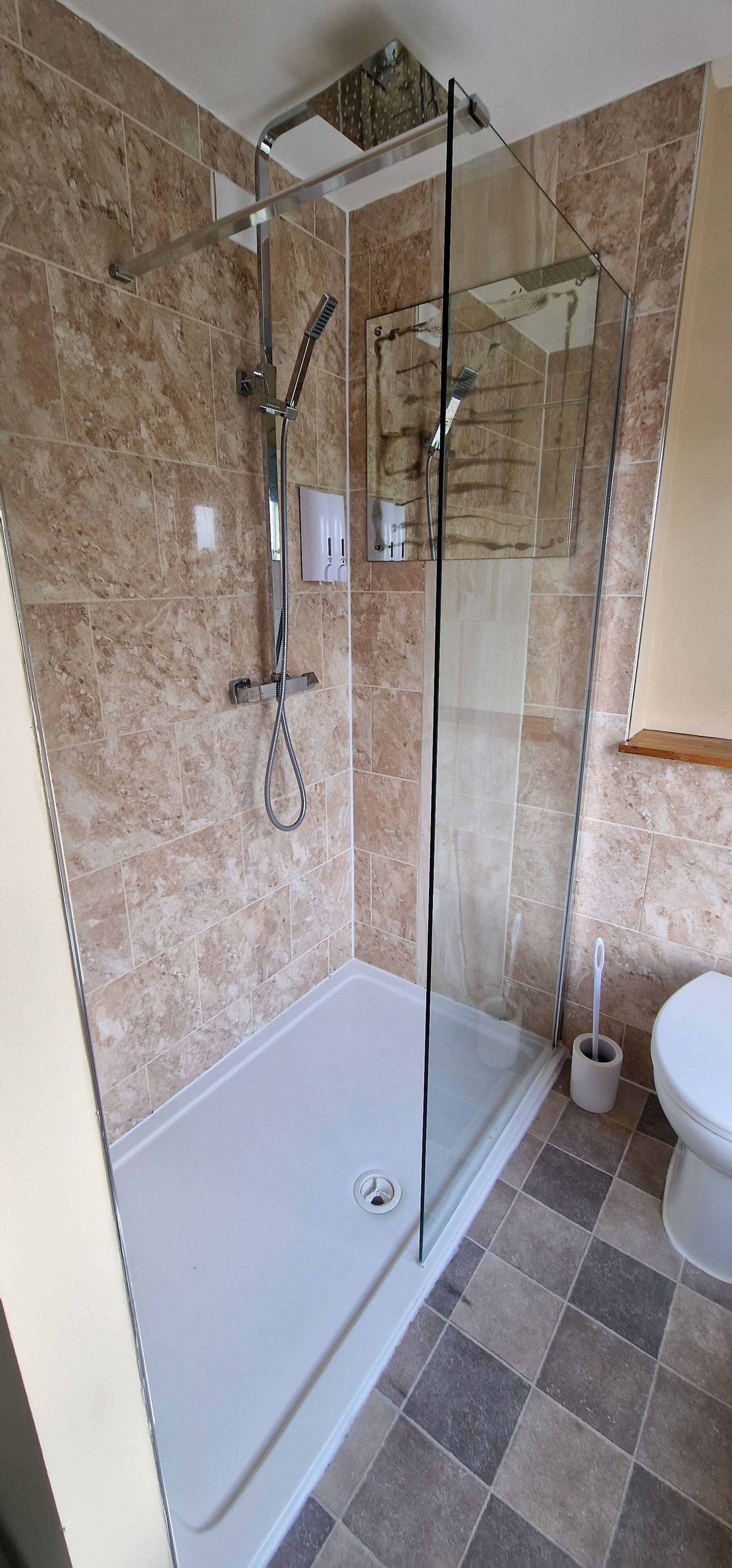 A modern bathroom with a glass-enclosed shower, a white toilet, and a marble-tiled floor.