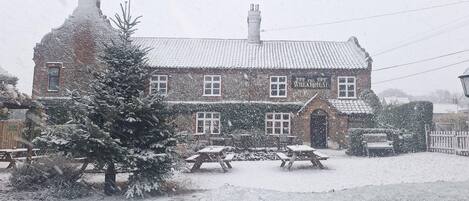 Un edificio in mattoni con un'insegna che recita “The Wheat Sheaf”. La neve ricopre il terreno e gli alberi.
