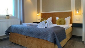 A neatly made bed with towels, a headboard, and wall-mounted lights. - Pension Gesundbrunnen (Mueglitztal)