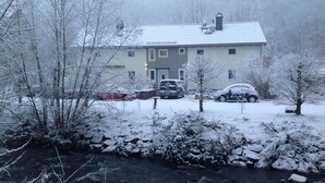 A house with a sloped roof, a front porch, and a driveway with parked cars. - Pension Gesundbrunnen (Mueglitztal)