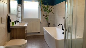 A modern bathroom with a toilet, sink, and bathtub. - Pension Gesundbrunnen (Mueglitztal)