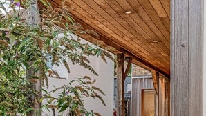 An outdoor patio area with wicker furniture and a wooden pergola.
