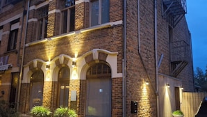 A brick building with arched windows and a balcony.