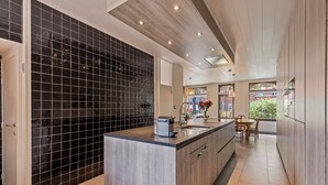 A modern kitchen with a black tiled backsplash, wooden cabinets, and a central island.