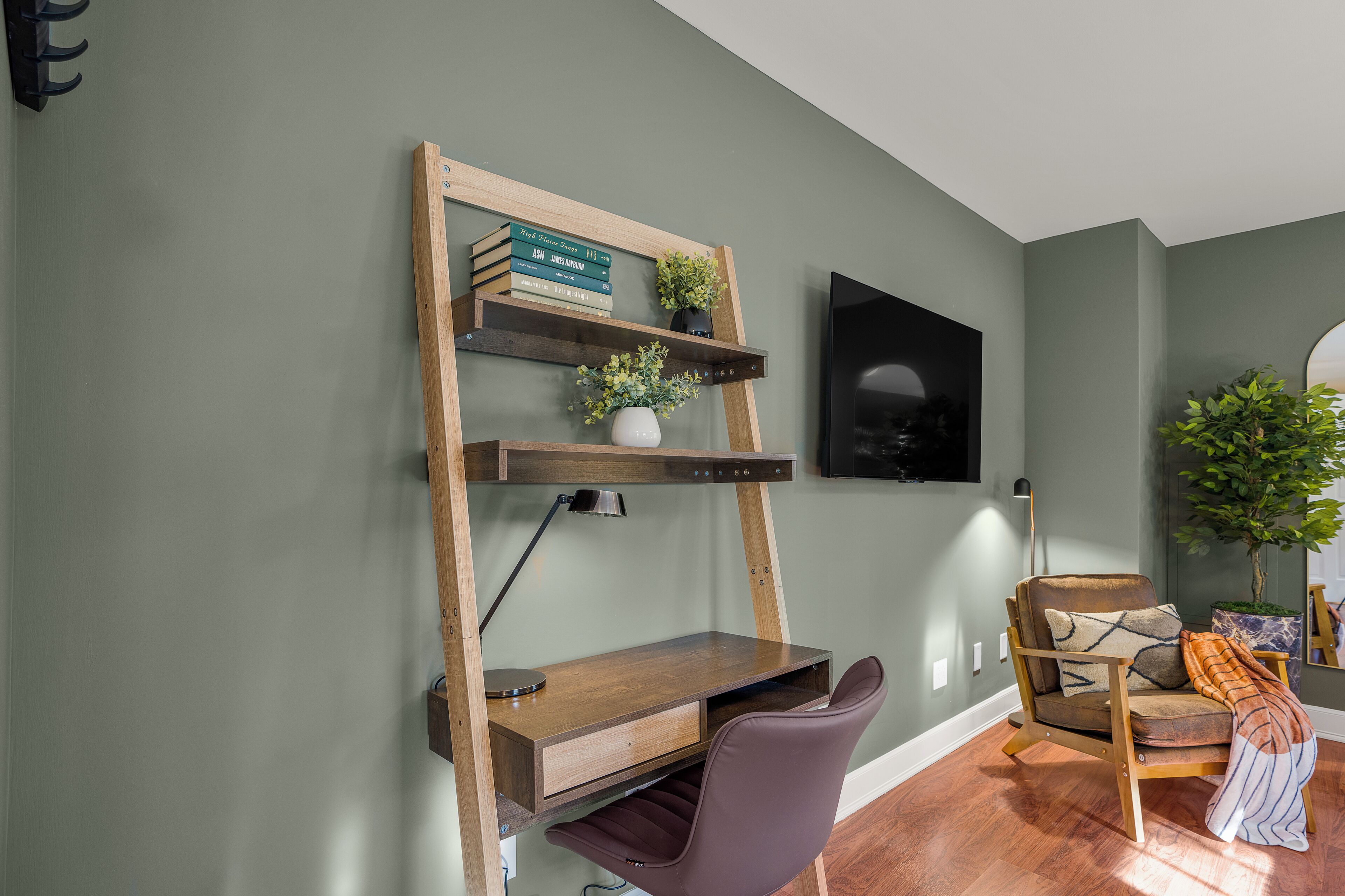 A study area with a desk, chair, shelving unit, and a television.