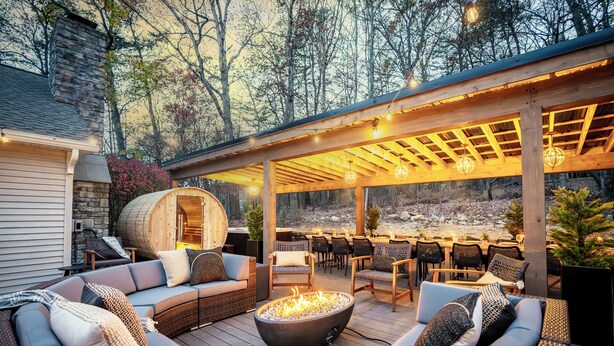 Une terrasse extérieure dotée d’un foyer, d’un espace salon et d’une partie couverte agrémentée de guirlandes lumineuses.