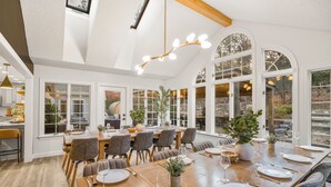 Un vaste espace dédié à la salle à manger, avec une longue table en bois dressée pour le repas, entourée de chaises.