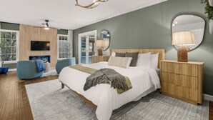 A modern bedroom with a large bed, a wooden headboard, a ceiling fan, and a TV mounted on the wall. - Grand and Gorgeous in Massanutten (McGaheysville)