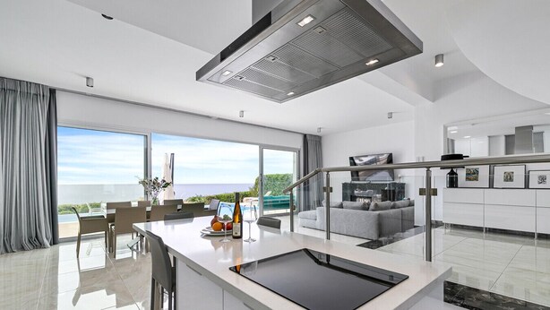 A modern kitchen with a large island, a dining area with a view, and a living space with a fireplace.