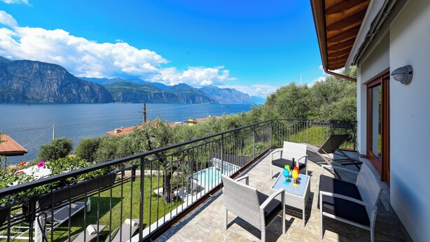 A balcony with outdoor furniture, a pool, and a scenic view of mountains and a lake. - MAISON SABINA WITH WONDERFUL LAKE VIEW, HYDROMASSAGE AND PRIVATE GARDEN (BRENZONE SUL GARDA)