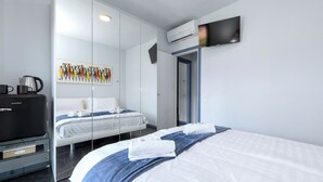 A modern hotel room with a large bed, a flat-screen TV mounted on the wall, a coffee machine, and a painting on the wall. - MAISON SABINA WITH WONDERFUL LAKE VIEW, HYDROMASSAGE AND PRIVATE GARDEN (BRENZONE SUL GARDA)