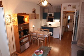 A compact kitchen with a dining area, wooden cabinets, a microwave, and a small table with chairs. - 10m from ski slopes, 4th floor, view ski slopes, balcony, tv, 22m², Les Orres (Les Orres)