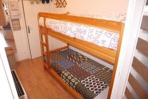 A bunk bed with patterned bedding, a wooden ladder, and a door with a key lock.