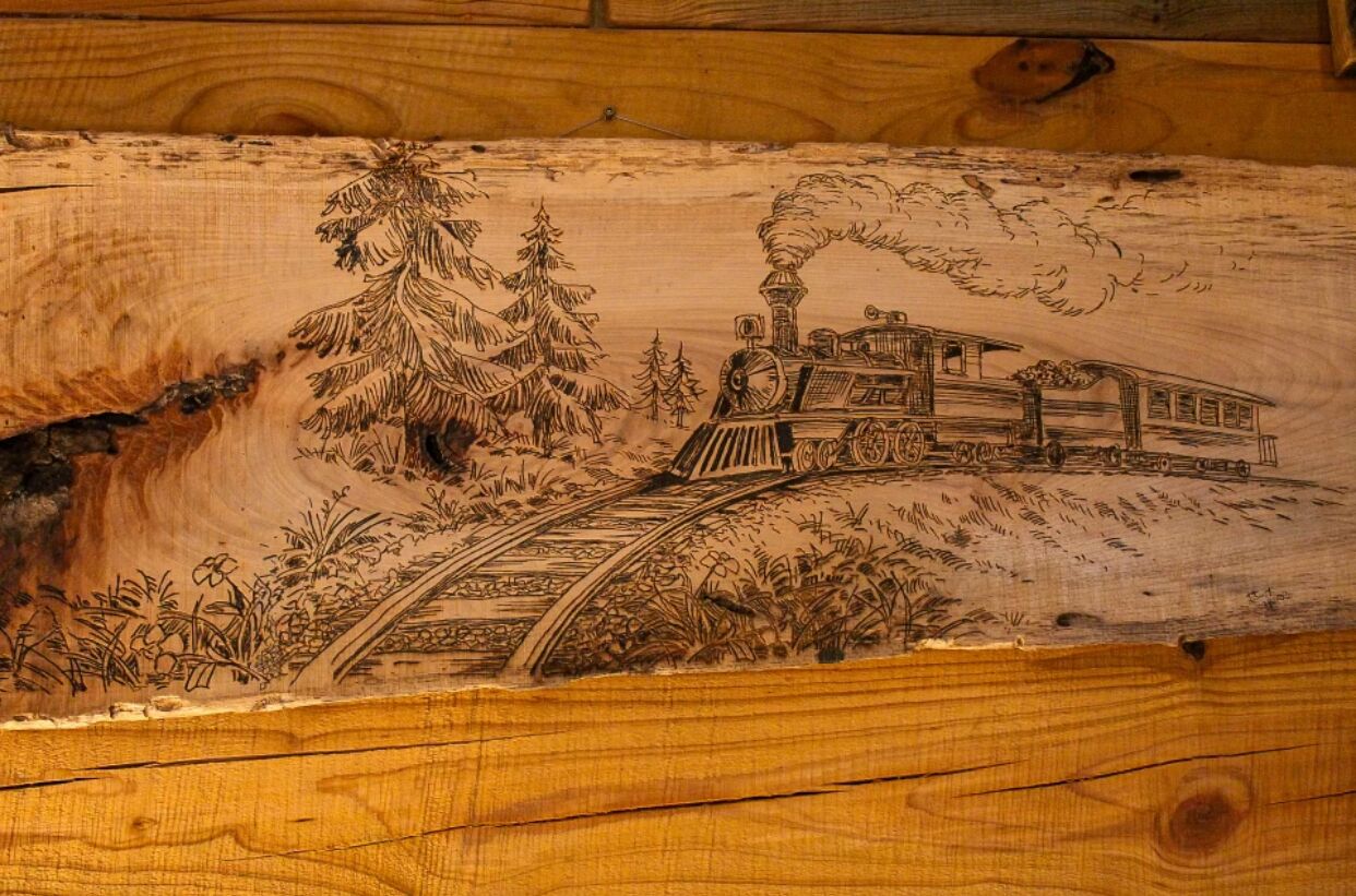 Intrincada talla en madera de un tren sobre un puente, con árboles y follaje.