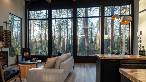 A modern kitchen with large windows, a built-in bench, and a wooden countertop. - Brand New Black Fox Cabin (Sprucedale)