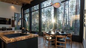 A modern kitchen with a large island, wooden dining table, and chairs. - Brand New Black Fox Cabin (Sprucedale)