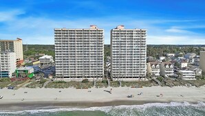 Un hotel sulla spiaggia con diversi piani, una spiaggia sabbiosa davanti e vista sull'oceano.