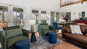 A spacious living room with a high ceiling, a dining area, and a staircase.