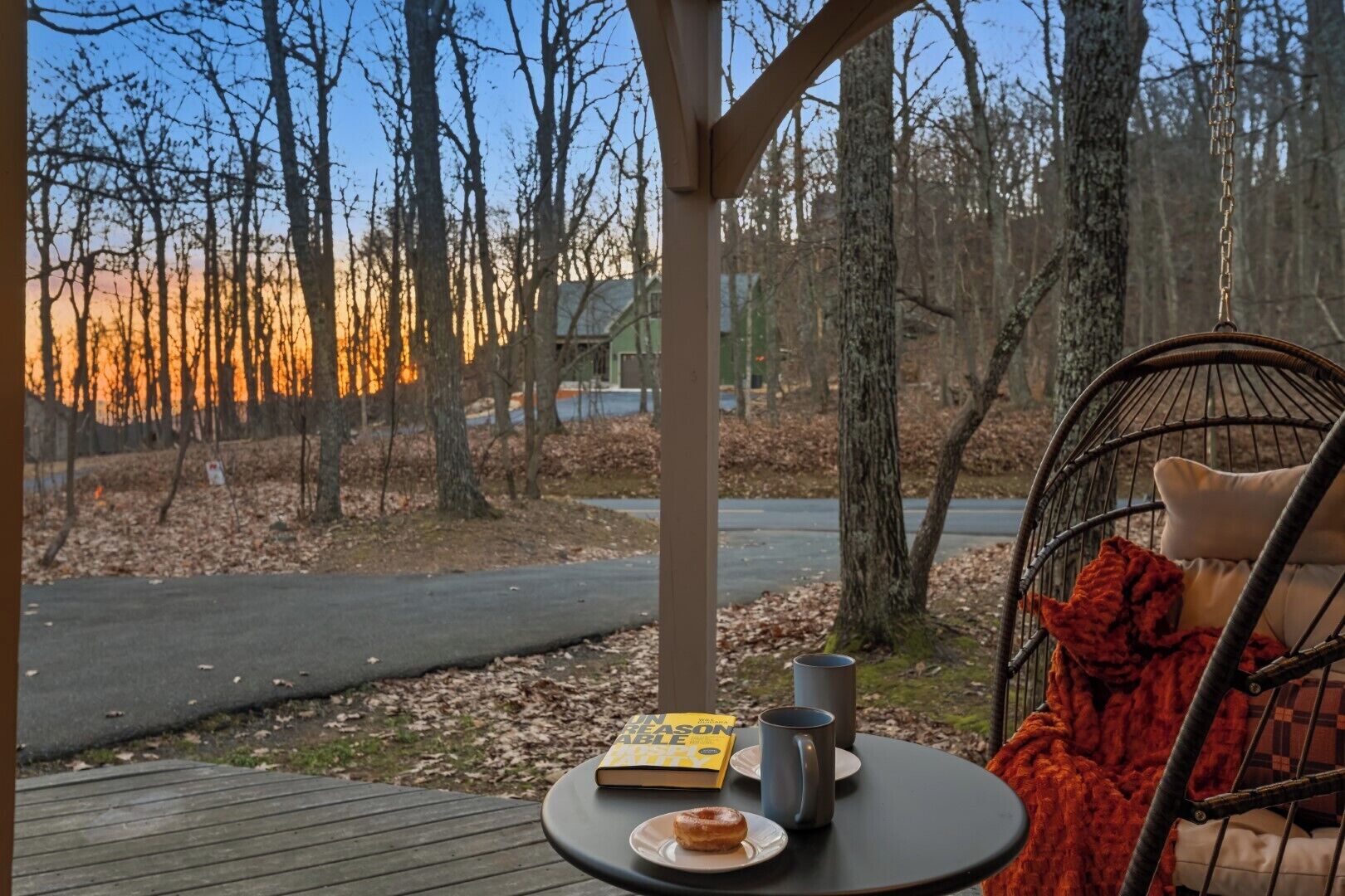 A cozy outdoor seating area with a chair, a table, a book, a mug, and a donut.