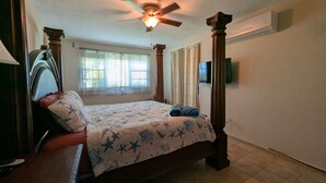 A bedroom with a bed, a ceiling fan, a window with curtains, and an air conditioning unit. - Ocean View Rooftop Villa Near El Yunque Sleeps 6 (Rio Grande)