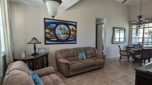 A spacious living room with a high ceiling, a large painting, and a ceiling fan. - Ocean View Rooftop Villa Near El Yunque Sleeps 6 (Rio Grande)