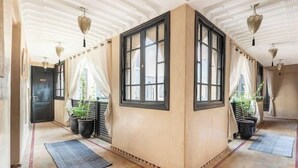 A corridor with a tiled floor, a black door, and a window with a black frame. - Riad basidi (Marrakech)