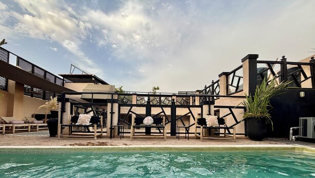 A pool area with lounge chairs and a pergola structure. - Riad basidi (Marrakech)