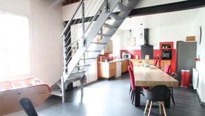 Une cuisine moderne avec une table à manger en bois, des chaises rouges et un escalier.