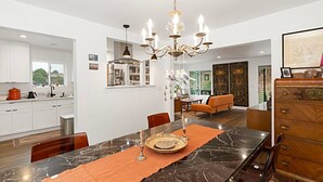 A modern kitchen with white cabinets, a marble island, and a chandelier. - Modern Peaceful Tucked Away With Private Office (San Diego)