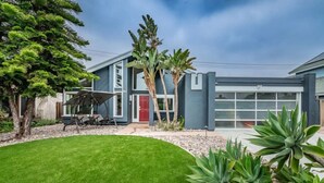 A modern house with a well-maintained lawn, a red door, and a garage.
