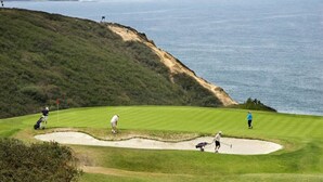 A golf course with a coastal view, a sand bunker, and a flagstick.
