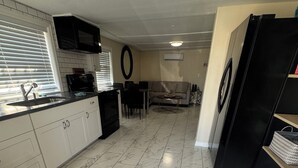 A kitchen with white cabinets, a black refrigerator, and a dining area with a sofa and chairs. - Cozy 2-bedroom apartment 3 mins away from
Tampa Int’l airport  (Tampa)