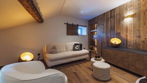 A cozy living room with a wooden wall, a sofa, a coffee table, and a lamp. - Grand Hôtel l'Ermitage Font-Romeu - Handwritten Collection (Font-Romeu-Odeillo-Via)