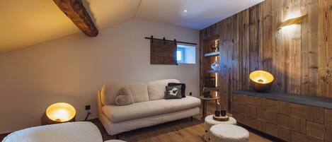 A cozy living room with a wooden wall, a sofa, a coffee table, and a lamp.