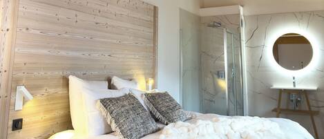 Ein Schlafzimmer mit Holzbalkendecke, einem Bett mit weißer Bettwäsche, einem runden Spiegel über dem Bett und einem Nachttisch aus Holz.