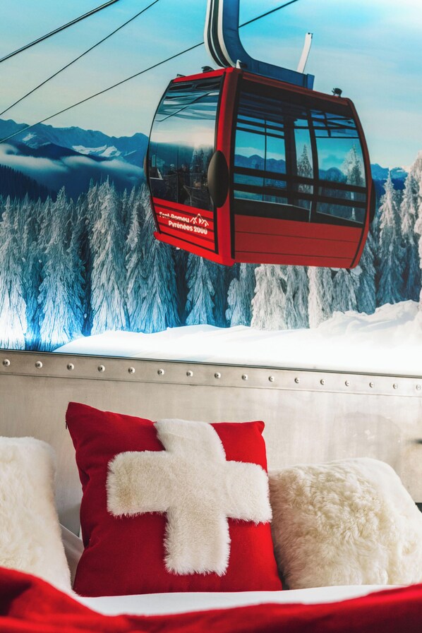 A bed with red and white pillows, a red cable car in the background, and a snowy mountain landscape. - Grand Hôtel l'Ermitage Font-Romeu - Handwritten Collection (Font-Romeu-Odeillo-Via)