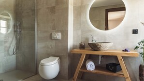 A modern bathroom with a glass-enclosed shower, a white toilet, a wooden vanity with a large round mirror, and a stone sink. - Grand Hôtel l'Ermitage Font-Romeu - Handwritten Collection (Font-Romeu-Odeillo-Via)