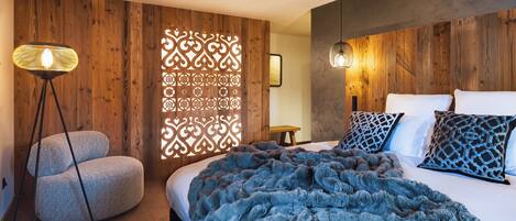 Un dormitorio con una cama grande, un panel decorativo en la pared, una lámpara de pie y una mesita.