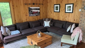 A cozy living room with a sectional sofa, a small table, and a chair.